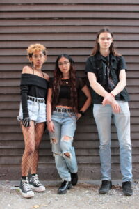 Image of NERiMA leaning against a wall wearing light blue denim bottoms and black tops.